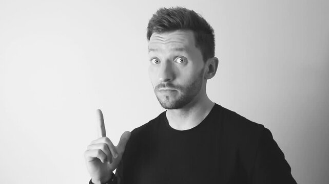 Slow motion footage of a man having and coming up with an idea by raising his finger up and having an expression of realizing. Video is in slow motion and 4k edited into a black, white colors.