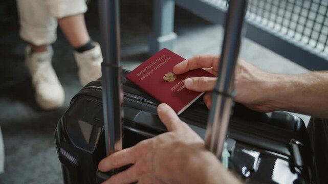 Waiting at the airport. passenger holding a European passport waiting for his flight. personal belongings, luggage or trolly for traveling purposes. delays in flight. bored man waiting impatiently. EU