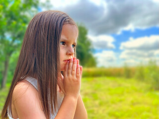 Fototapeta premium Little girl praying, looking at the sky with hope, portrait. Little girl praying.