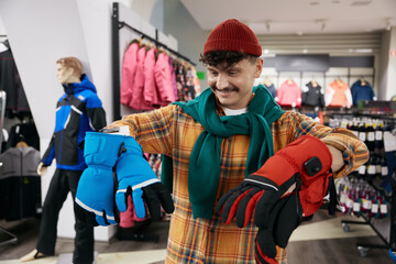 Smiling positive hipster man bicyclist choosing sportive protective gloves