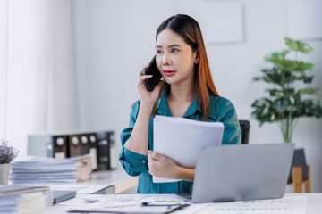 Cheerful business Asian woman employee making telephone call share good news about project work in office workplace, business  financing accounting banking concept.