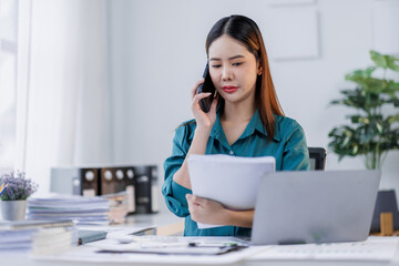 Cheerful business Asian woman employee making telephone call share good news about project work in office workplace, business  financing accounting banking concept.