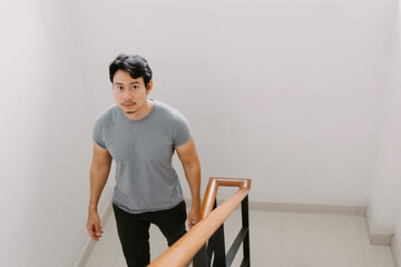 Asian Thai man walking down the stairs and looking at camera.