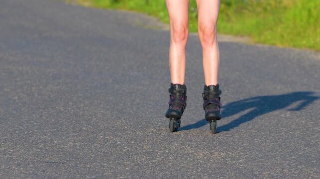 Close-up of a person rollerblading on a paved road, legs and skates in motion.