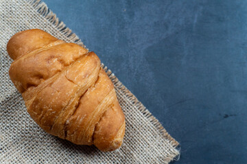 top view a croissant on top gunny sack on dark table