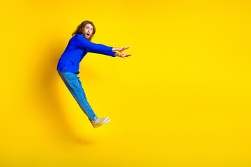 Photo of worried nervous funny man wear trendy blue clothes fly empty space isolated on yellow color background