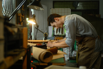 Handsome asian craftsman working meticulously in a workshop. Small business and handmade concept