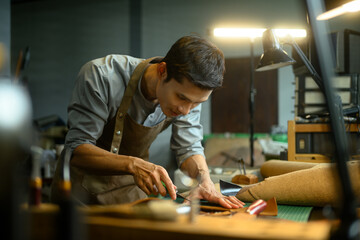 Handsome asian craftsman working meticulously in a workshop. Small business and handmade concept