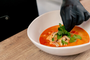 in a fast food establishment large chef in a black uniform prepares Japanese udon soup from...