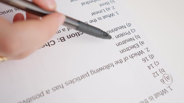 Female circles correct answers in standard exam test paper with black pen. Student filling up the answer sheet, choosing right answer, close up shot.