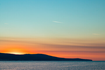 dawn over the sea, traces of airplanes in the multi-colored sky