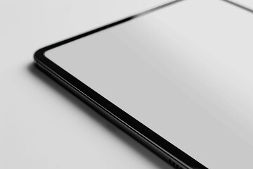 This image shows a close-up view of the corner of a sleek tablet placed on a light grey surface with the edge in focus and the screen reflecting light.