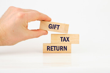 Text GIFT TAX RETURN on wooden blocks with a man's hand on a white background