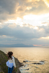 Woman looking to the sunset over the sea in Basque Country 
