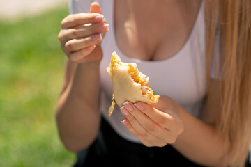 close-up in restaurant on the street a beautiful long-haired girl in sunglasses sits at a table eating pita daytime lunch