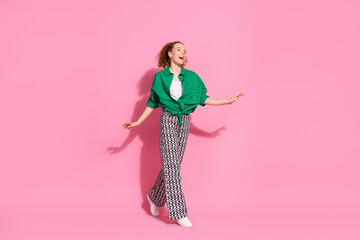 Full length photo of shiny attractive lady dressed green shirt dancing walking empty space isolated pink color background