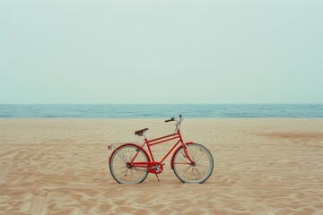 Fototapeta premium Red vintage bicycle standing on a beautiful sandy beach with the ocean in the background