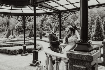 Obraz premium A bride and groom are standing in front of a gazebo, with the bride wearing a white dress