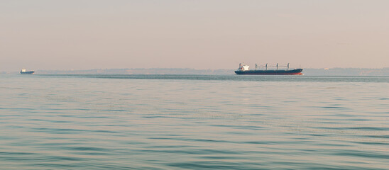 A black cargo ship moving in the water of the Black Sea. A large cargo ship is sailing in a sea bay