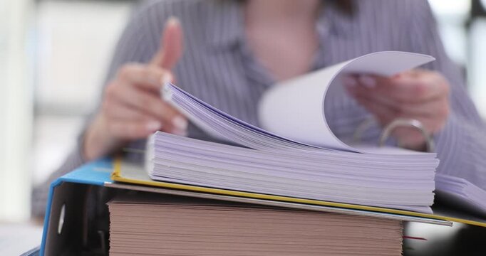 Female worker flips through pages of folder in office