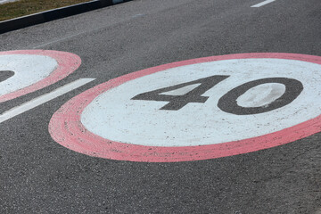 A 40 km per hour speed limit sign is painted on the asphalt of the road.