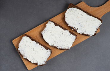 Home made rye bread on a wooden cutting board with curd cheese and ricotta