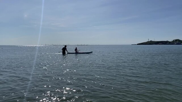 Silhouette of a child on a SUP board and an adult next to him against the backdrop of the clear horizon of the black sea. High quality 4k footage