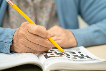 Alzheimer disease AD, Asian elderly woman playing sudoku puzzle game to practice for dementia...