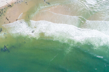 waves on the shore of a beach in the summer, aerial top view with drone. Maritime seascape