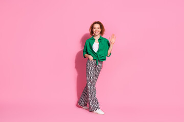Full length photo of cheerful pretty lady dressed green shirt walking waving arm hi empty space isolated pink color background