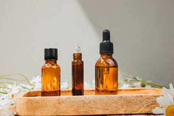Set of natural cosmetics. Amber bottles with facial, bath liquid on a wooden table with white field chamomile. Front view