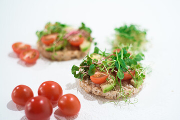 Bright vegan tomato and avocado snacks. Sandwiches with tomato, microgreen and baby spinach.
