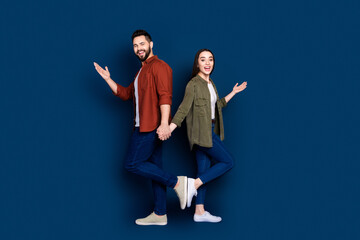 Photo of cheerful glad couple wife husband wear stylish clothes hold hands announce discount isolated on dark blue color background