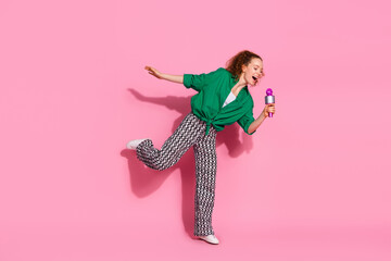 Full length photo of cheerful pretty lady dressed green shirt sining mic empty space isolated pink color background
