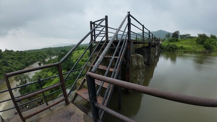 Fototapeta premium Railings provide safety at a small dam under a cloudy sky, ensuring protection for visitors and the surrounding area.