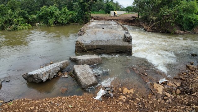 Damaged small check dam with water cascading over it, producing a gentle sound of flowing water in the environment.
