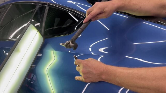 Removal of dents without painting. PDR technology for car body repair. PDR. The mechanic at the auto shop with tools to repair dents in car body. Body repair.
