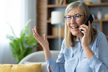 Senior woman with glasses talking on phone indoors looking upset or frustrated. Elderly lady having...