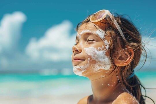 Happy and smiling young girl protecting her face with suncreen at the beach during summer family vacation. Empty space for copy