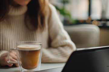 Minimal aesthetic photo of a woman in a cozy sweater with a coffee and laptop, perfect for lifestyle and cozy themes.