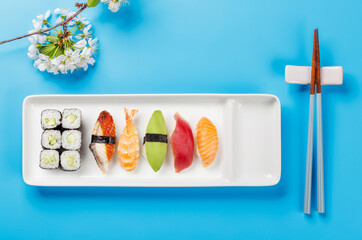 Sushi plate adorned with cherry blossom branch and chopsticks, epitomizing Japanese food culture
