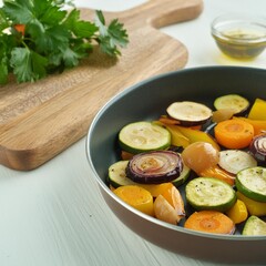Healthy roasted vegetables in the cooking pan close up, wooden cutting board and ingredients