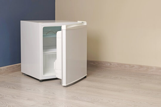Single chamber empty white open mini fridge with freezer above on floor. Home appliances. Food and food storage at home. 
