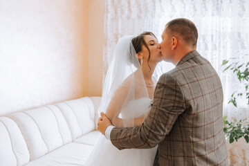 Fototapeta premium A man kisses a woman wearing a wedding veil. Scene is romantic and intimate