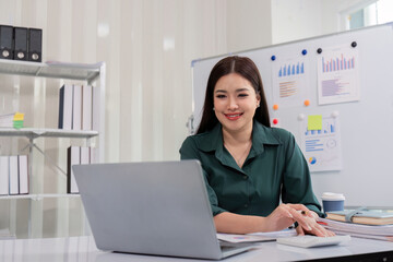 Professional Businesswoman Working on Laptop in Modern Office Environment with Charts and Graph