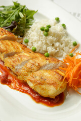 Pan fried chicken fillet served in tomato sauce with rice and fresh vegetables