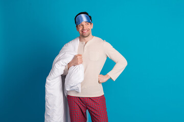 Photo portrait of attractive young man look empty space hold blanket dressed pajama sleepover good night isolated on blue color background