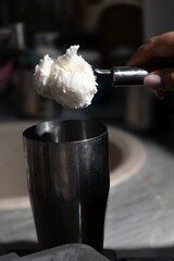 A ball of vanilla white ice cream is dropped into a glass for whipping a cocktail. Close-up. The process of making a milkshake. Vertical photo. High quality photo