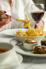 Woman eating french fries served on the restaurant table