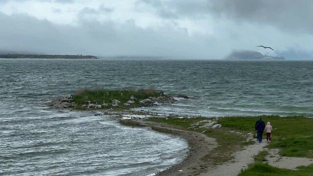 Family walks along quiet lakeside, dramatic scenery. Sevan lake, Armenia